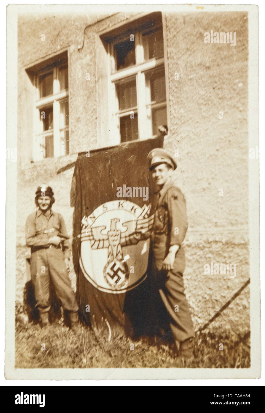 A large flag of the NSKK (National Socialist Automotive Division) Red cotton flag cloth, both faces display a multi-coloured symbol with national eagle and 'N.S.K.K.' in the centre. Reinforced corners, with flaws and holes. Dimensions 5 x 2 m. Comes with a photograph of two U.S. soldiers with captured NSKK flag. historic, historical, organisation, organization, organizations, organisations, 20th century, Additional-Rights-Clearance-Info-Not-Available Stock Photo
