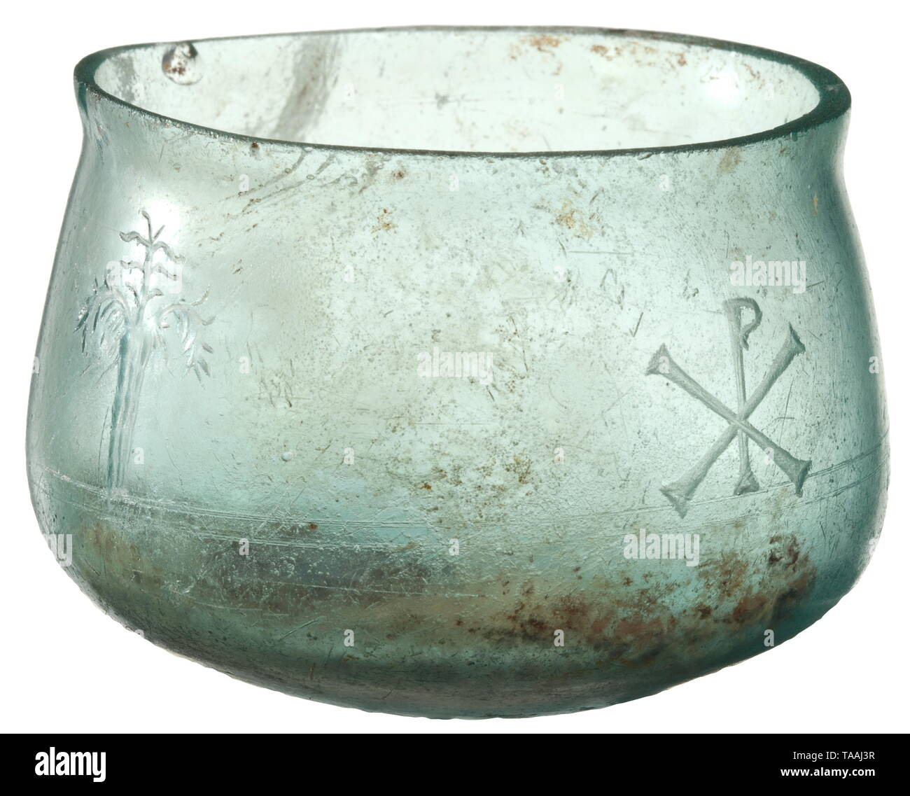 A late Roman glass cup cut with early Christian motifs, 2nd half of 4th century Transparent, slightly bellied cup with change in the lower quarter and re-cut rim. On the exterior above the inward curve two thin grooves, surmounted by four cut motifs: two trees flanking a lamb and a chi-rho symbol. High-quality work with minimal chippings at the edge, otherwise well preserved. In the interior partially chipped iris. Height 5.9 cm. Maximal diameter 8.3 cm. Provenance: Rhenian art dealer, Ex Coll. W.W, acquired in the 1980s. historic, historical, Ro, Additional-Rights-Clearance-Info-Not-Available Stock Photo