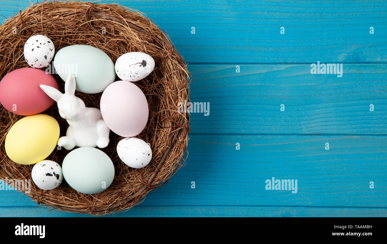 Happy easter nest blue wooden background with colorful easter eggs and easter bunny Stock Photo