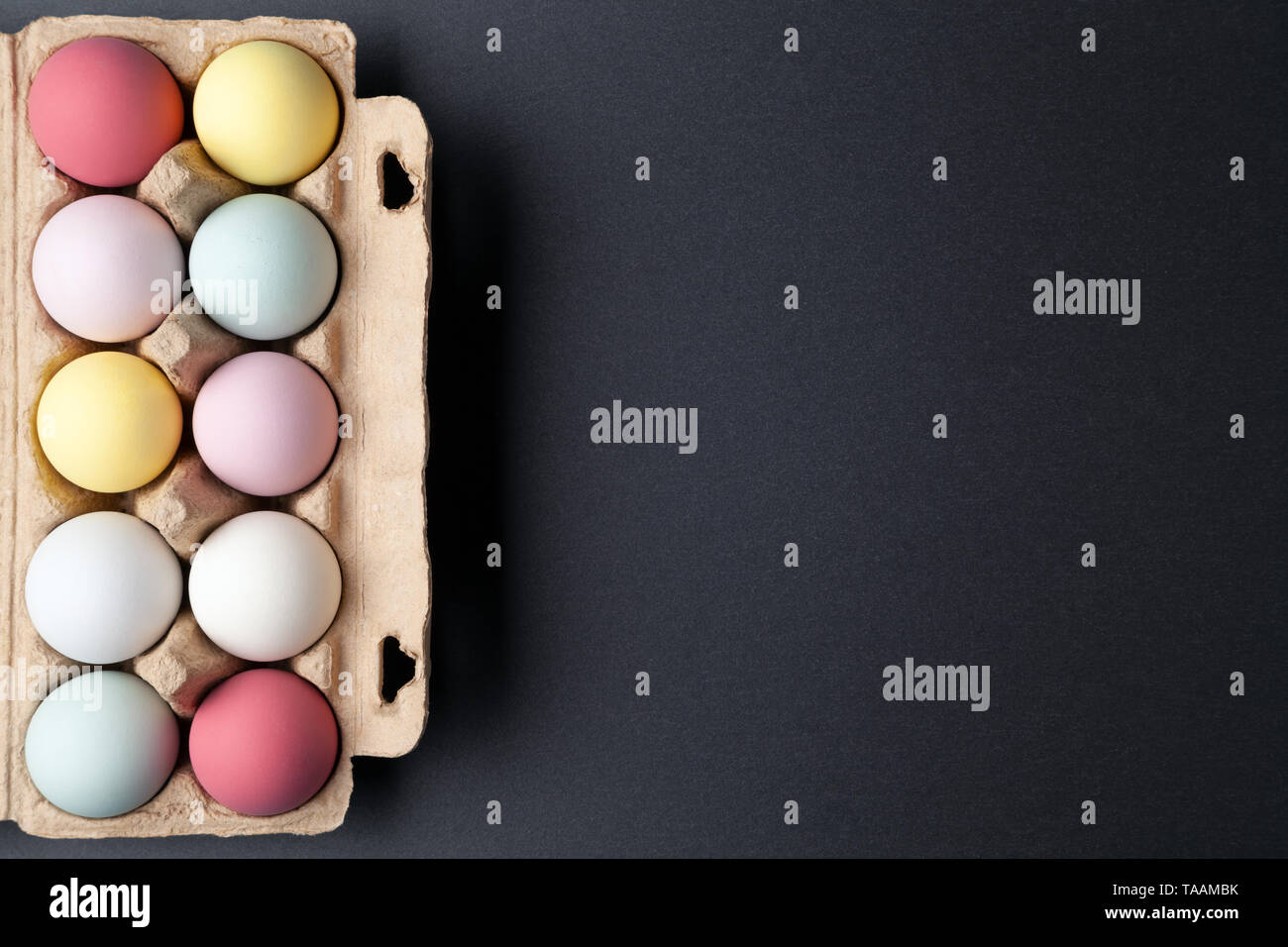 Colorful easter eggs in an egg carton on graphite texture background Stock Photo