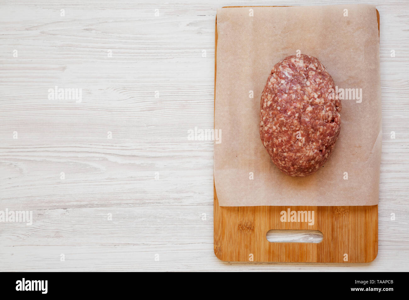 Fresh raw grass fed ground beef on a bamboo board, top view. Copy space