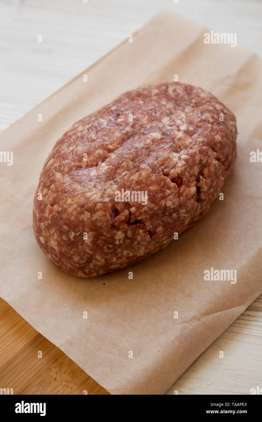 Fresh raw grass fed ground beef on a bamboo board, side view. Closeup