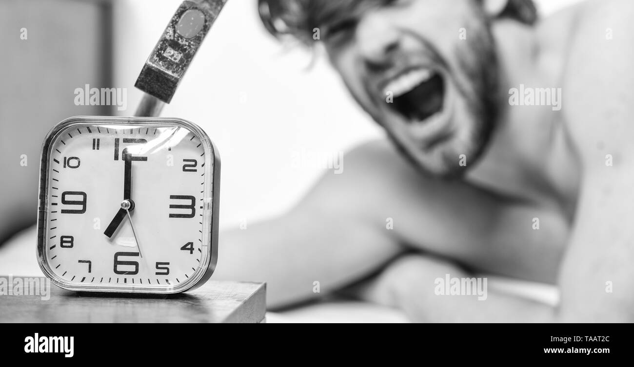 Annoying ringing alarm clock. Man bearded annoyed sleepy face lay