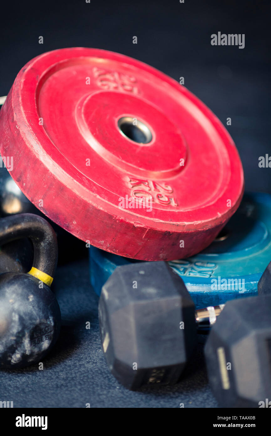Pile of weight plates, dumbbells, and kettlebells on gym floor Stock Photo Alamy
