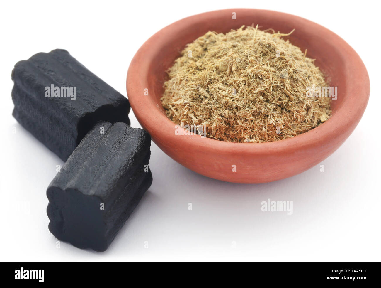 Liquorice powder in a bowl and candy over white background Stock Photo