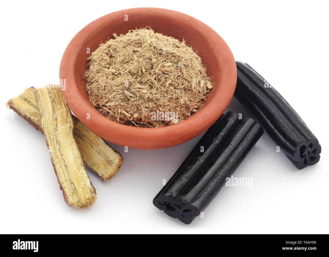 Liquorice powder in a bowl and candy over white background Stock Photo