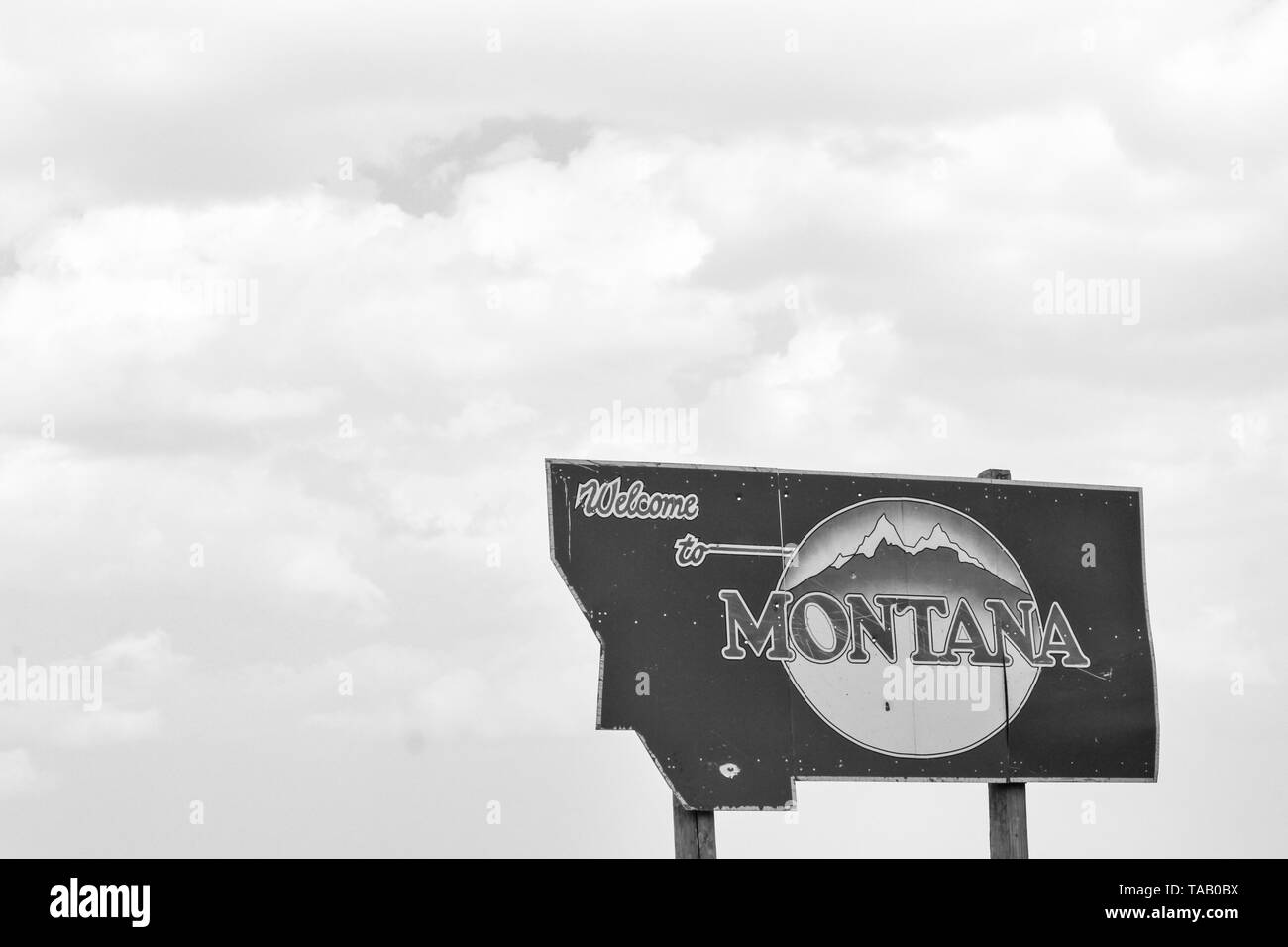 Roadside sign against cloudy sky, reading 'Welcome to Montana'.  Black and White. Stock Photo
