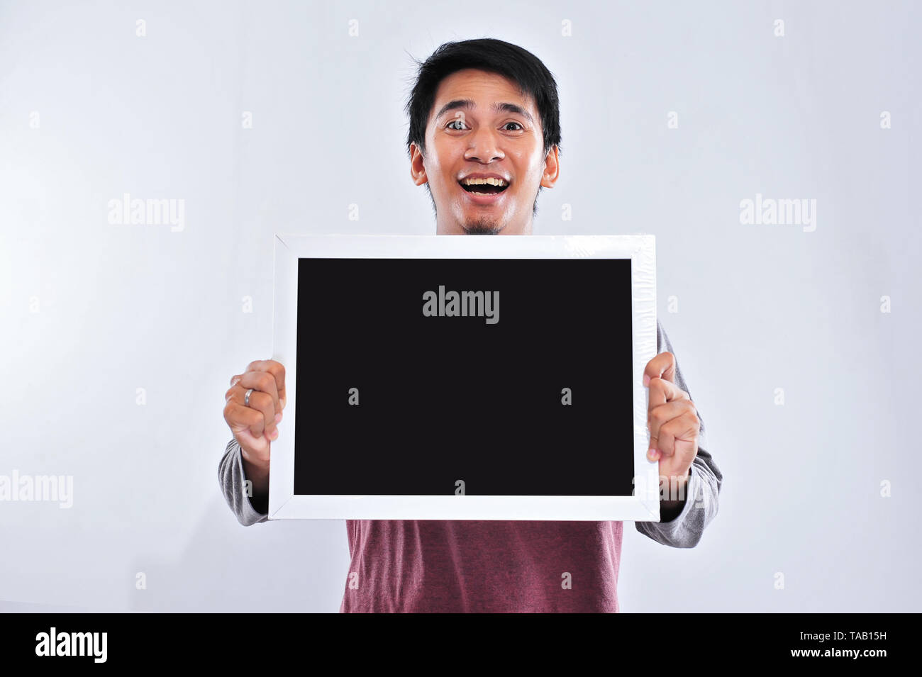 Happy young handsome asian man holding and showing blank blackboard or board ready for your text. Copy space Stock Photo