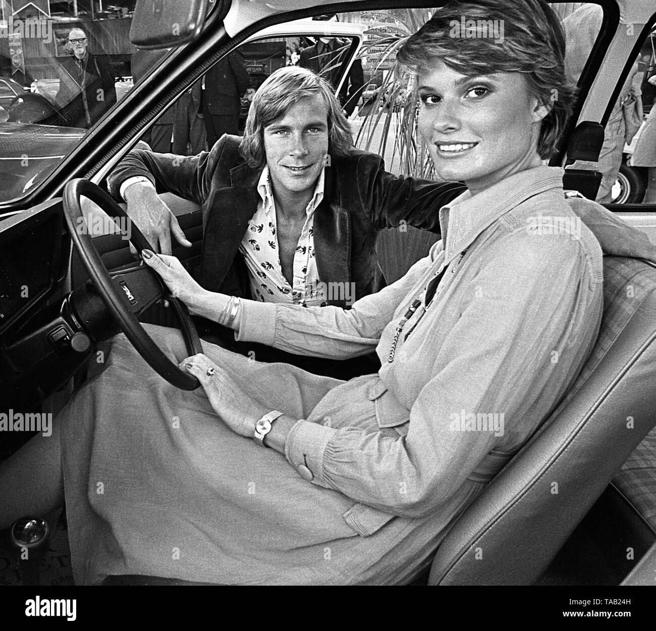AJAXNETPHOTO. 1975. PORTSMOUTH, ENGLAND - MOTOR RACING WORLD CHAMPION - JAMES HUNT (LEFT) AND HIS WIFE SUZY (RIGHT) VISITING THE UNITED SERVICES GARAGE TO REVIEW THE UK'S FIRST ELECTRIC CAR. PHOTO:PETER EASTLAND/AJAX REF:7505 36 2 Stock Photo