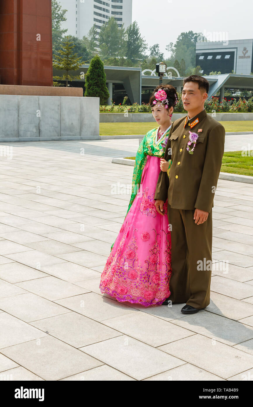 Pyongyang, North Korea - July 29, 2014: Young Korean couple in Victorious Fatherland Liberation War Museum. Newlyweds are photographed against the bac Stock Photo