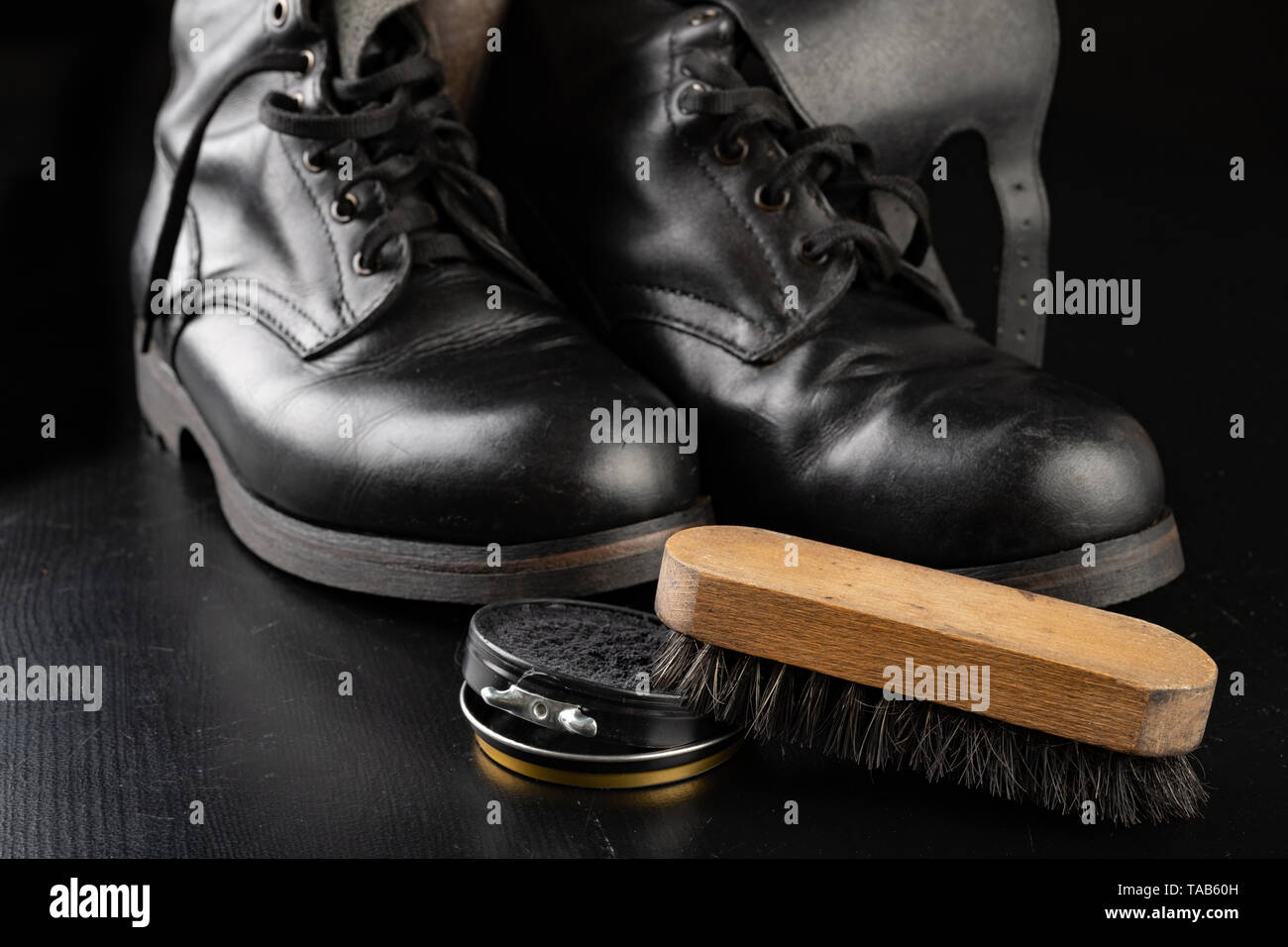 Shoe polish, brush and black military boots. Polishing and cleaning shoes  on a black table. Dark background Stock Photo - Alamy