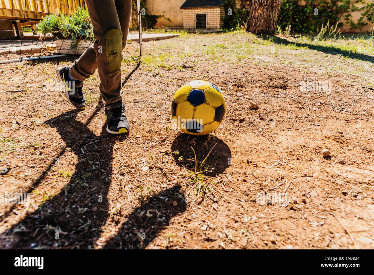 Child playing with a soccer ball in the yard of his house in the sun