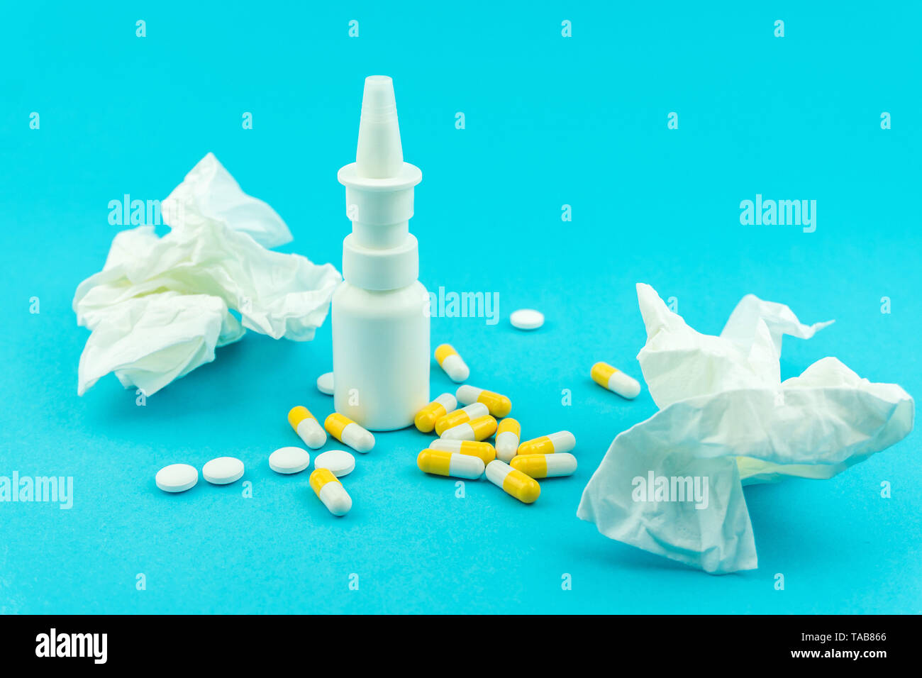 Pills, nasal spray and wrinkled tissue against blue background, cold or