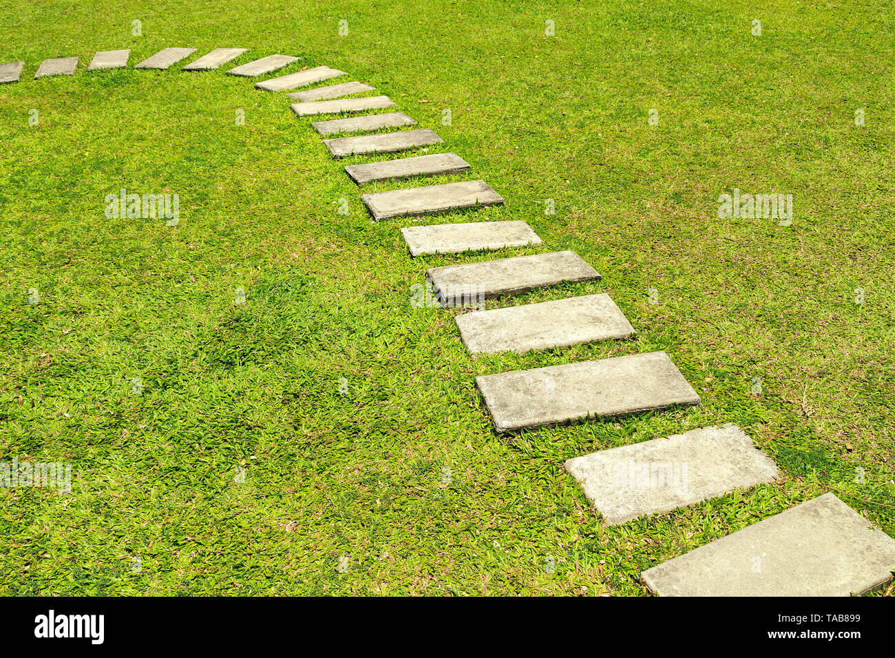 Stone tile pavement on green grass lawn Stock Photo