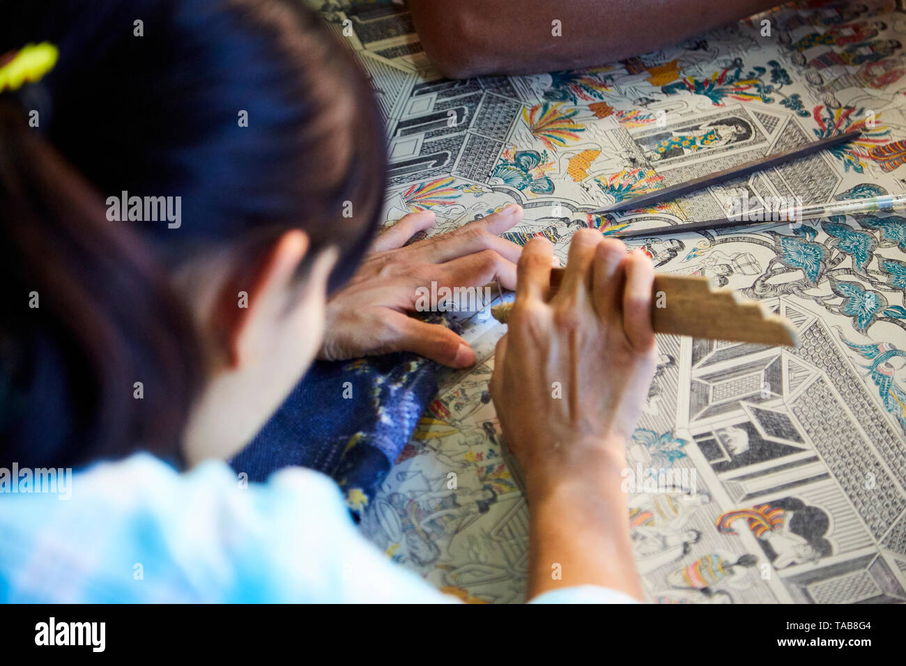 Woman working etching designs into enamelware in marketplace in Bagan, Myanmar. Stock Photo