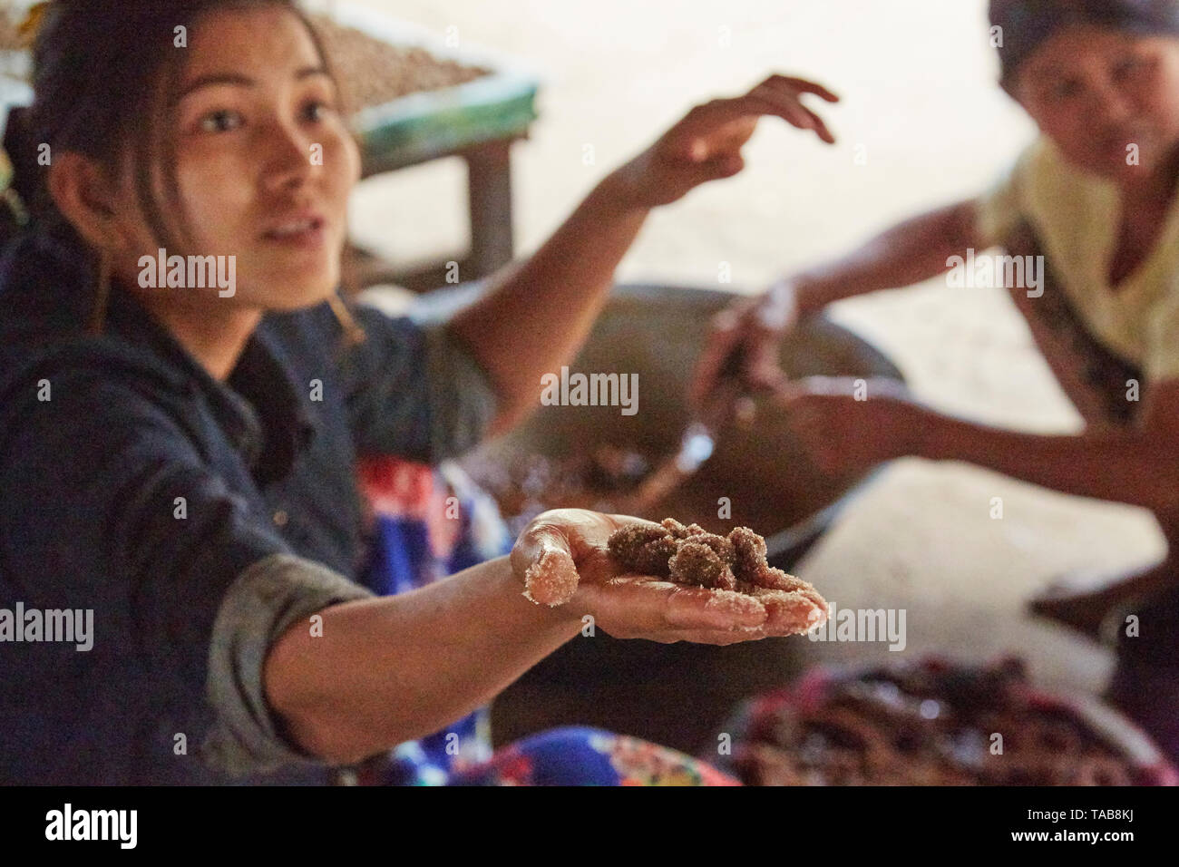 Woman at market in Bagan, Myanmar sells candies made from Palmyra sugar, held in her hand. Stock Photo