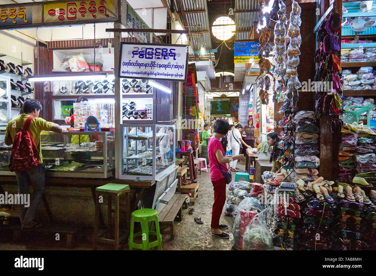 People shop in marketplace in Myanmar filled with shoes, clothing, and jewelry. Stock Photo