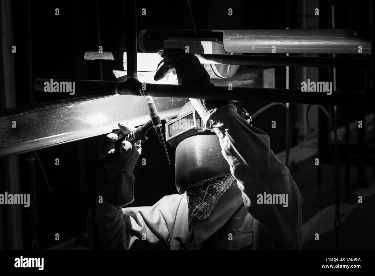Welding steel pipe with Mig-Mag method for industrial work. Black & White concept. Stock Photo