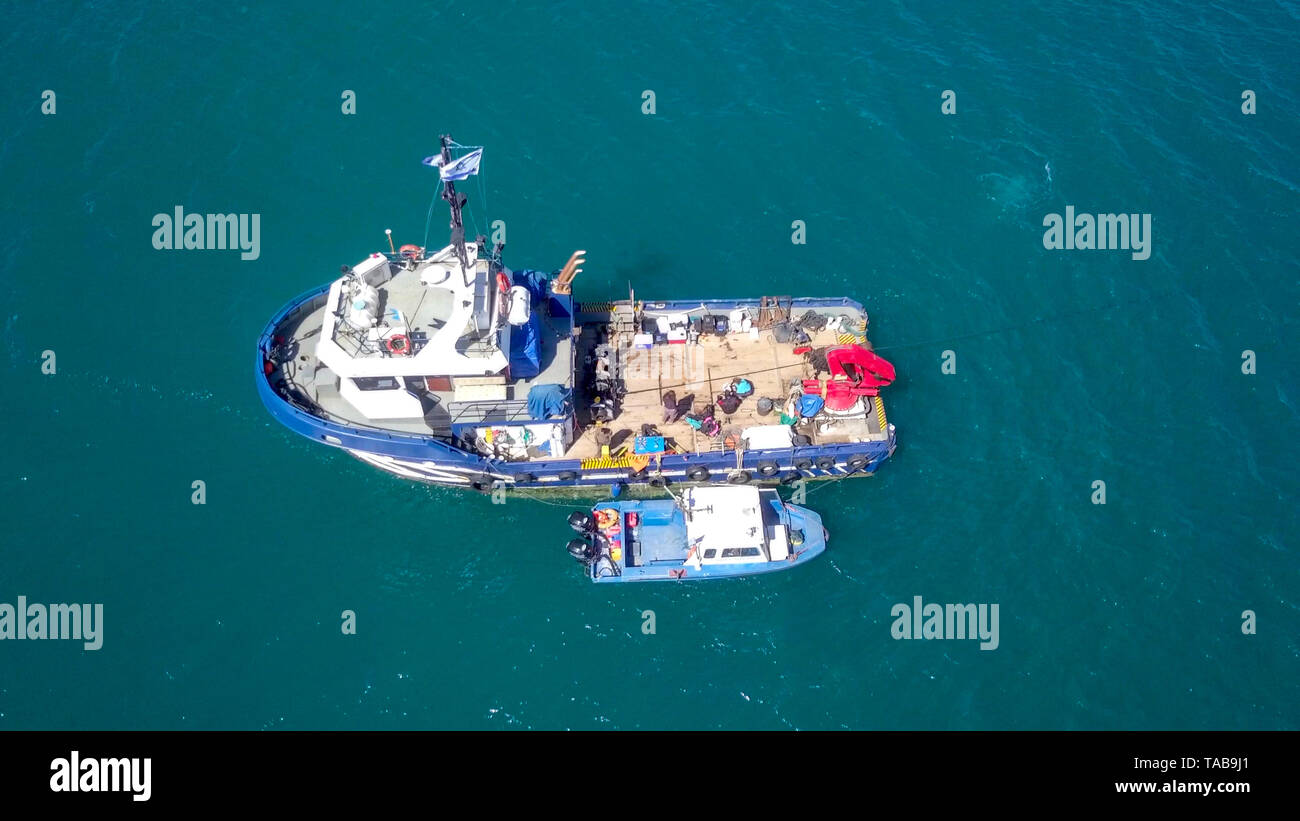 Fishing boat at sea with a smaller boat tied next to it - Aerial image. Stock Photo