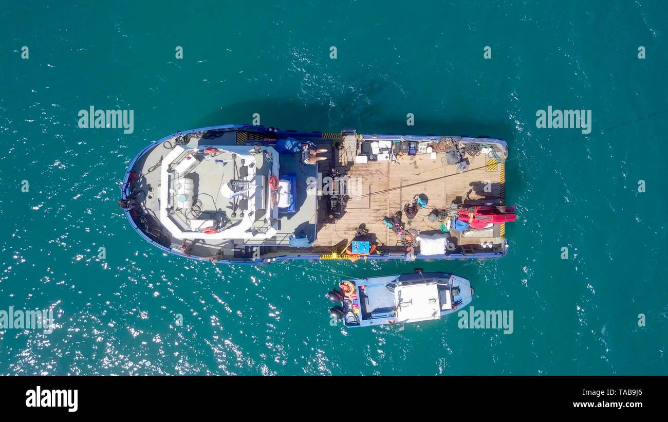 Fishing boat at sea with a smaller boat tied next to it - Aerial image. Stock Photo