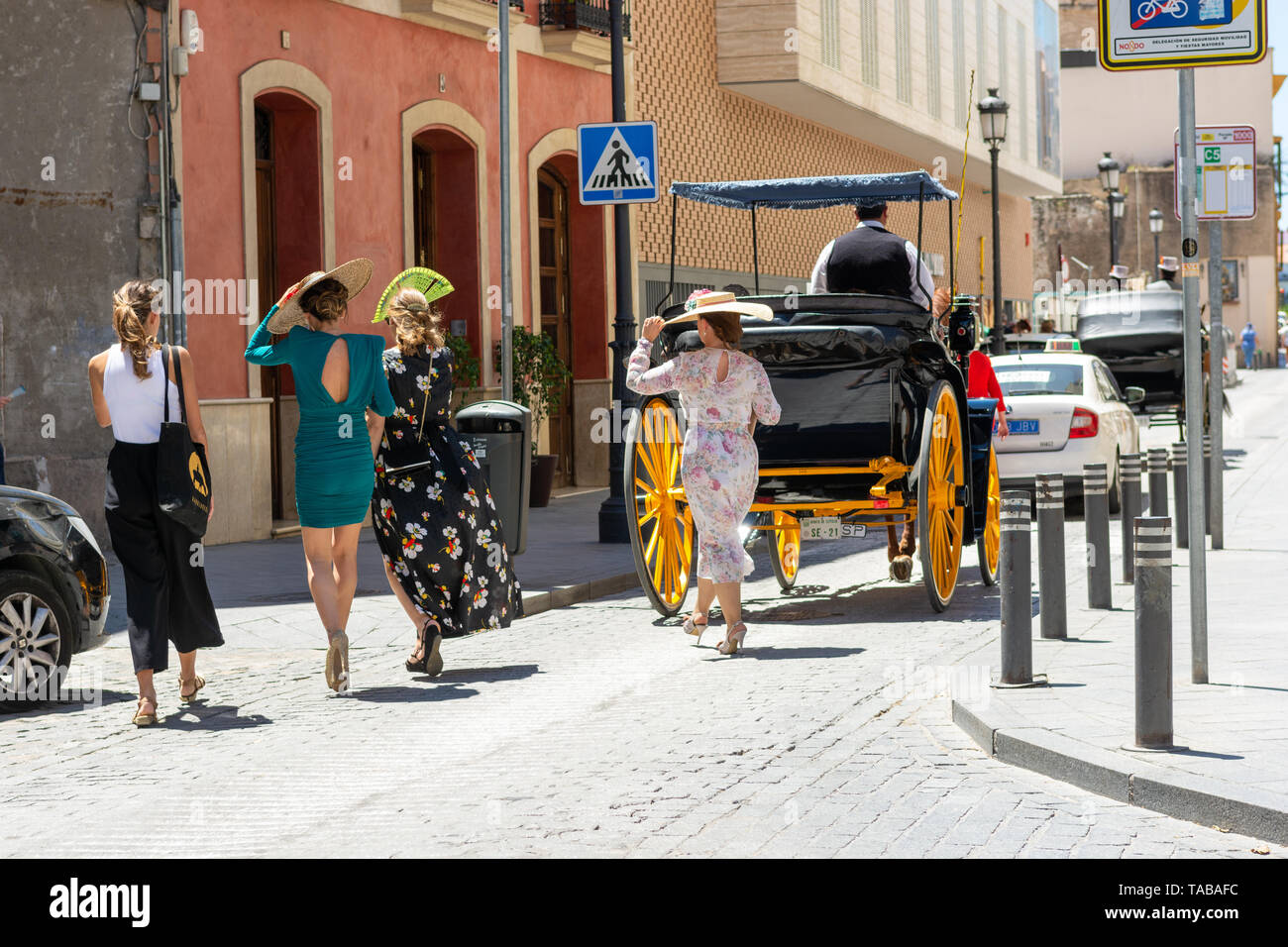 Glamorous wedding party guests following a horse drawn chariot, Seville, Andalusia region, Spain Stock Photo