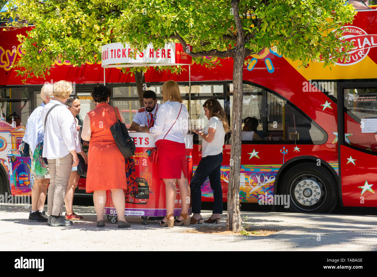 Tourists buying tickets for a hop-on hop-off sightseeing bus tour of Seville, Andalusia region, Spain Stock Photo