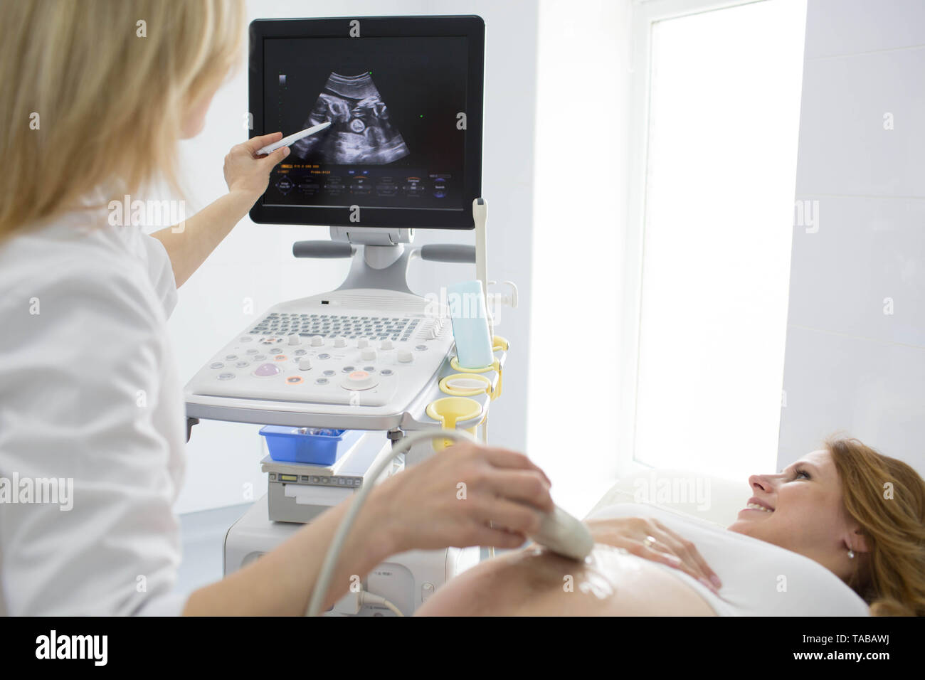 Happy woman looking at ultrasound results with her doctor in examination room Stock Photo
