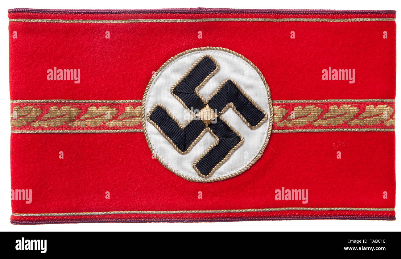 An NSDAP armband for 'Stellvertretender Gauleiter' Red wool, separately applied white disc, multi-piece black swastika piped in gold bullion twist cord. Applied to the centre is a single 16 mm machine woven horizontal strip of repeating gold oakleaves bordered with a double row of 1 mm gold wire piping. Outer edges finished with 1 mm gold wire piping and light blue rayon piping. Ends sewn together. USA-lot, see page 4. historic, historical, 20th century, 1930s, party organisation, party organization, organisations, organizations, organization, organisation, party, parties, , Editorial-Use-Only Stock Photo