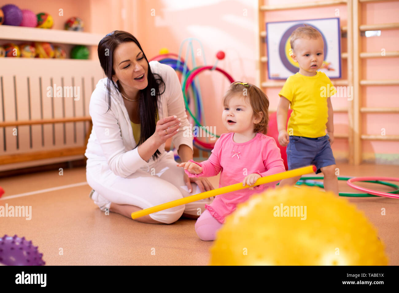 Group of babies in gym with nursery teacher Stock Photo Alamy