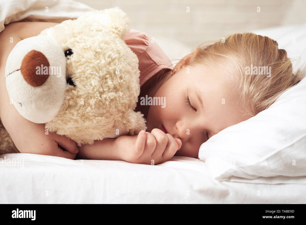 Cute little child girl sleeping with teddy bear in her bed Stock Photo