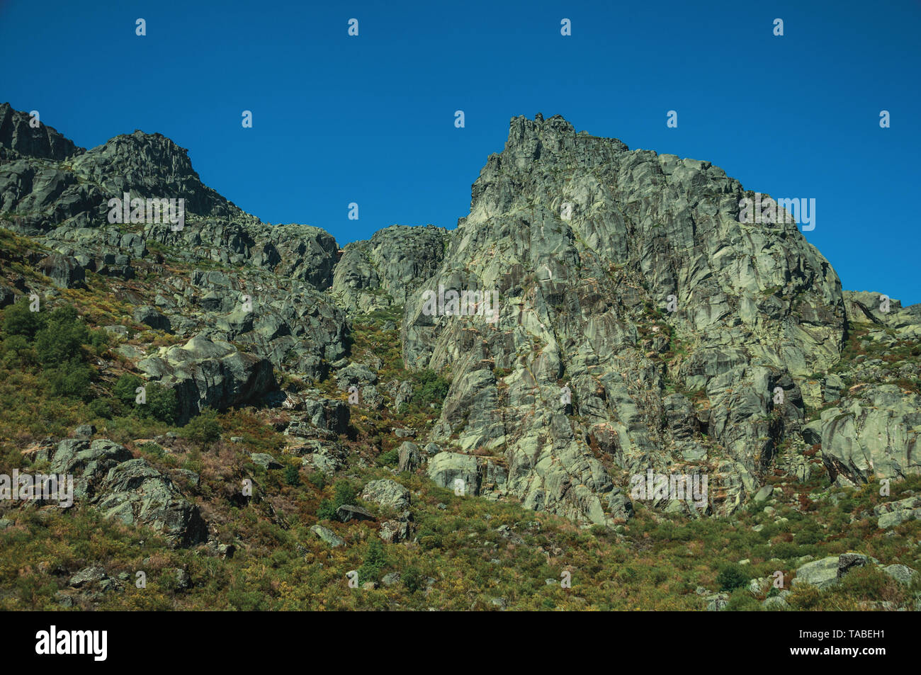 Mountainous landscape with rocky cliffs covered by bushes at the highlands of Serra da Estrela. The highest mountain range in continental Portugal. Stock Photo