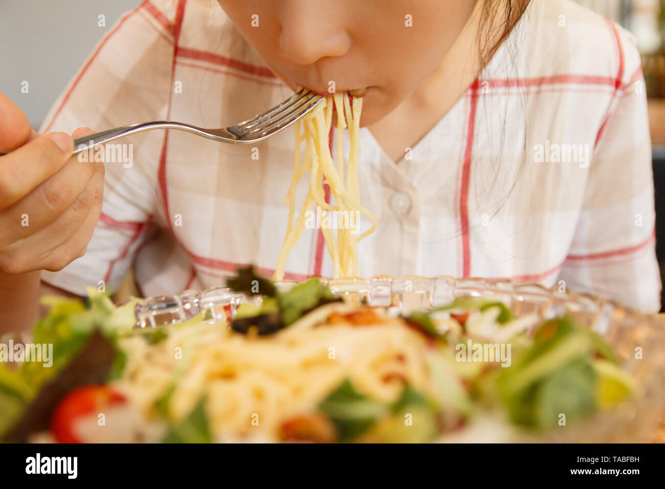Asian woman eating spaghetti with a fork Stock Photo