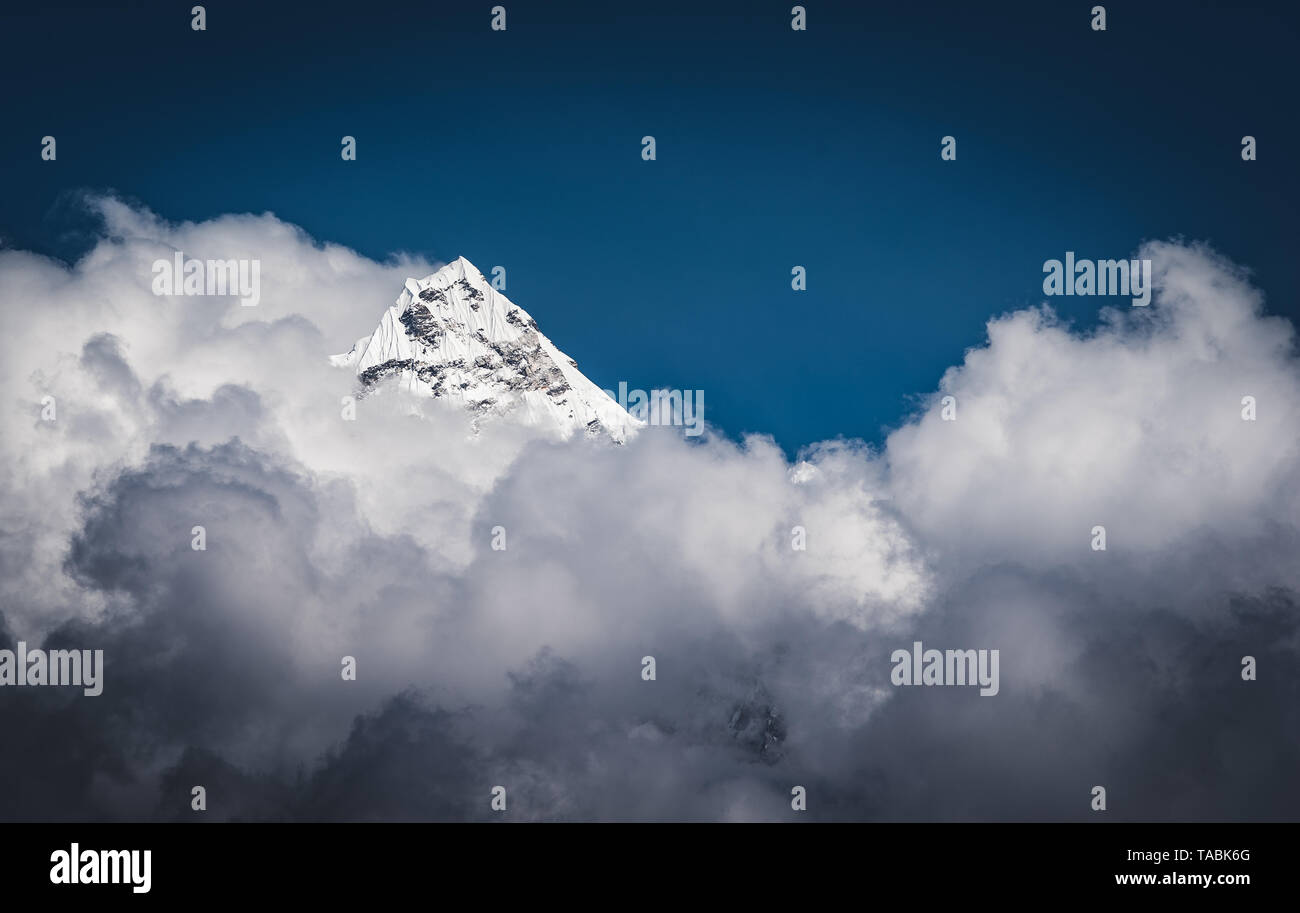 Landscape of rugged Himalayan mountain top peaking through the clouds. Stock Photo