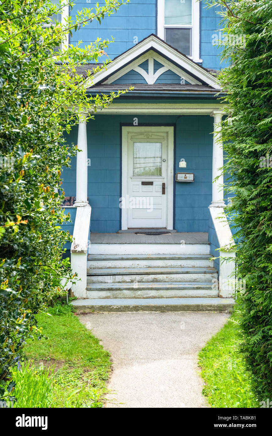 Main entrance of old family house with doorsteps and concrete pathway