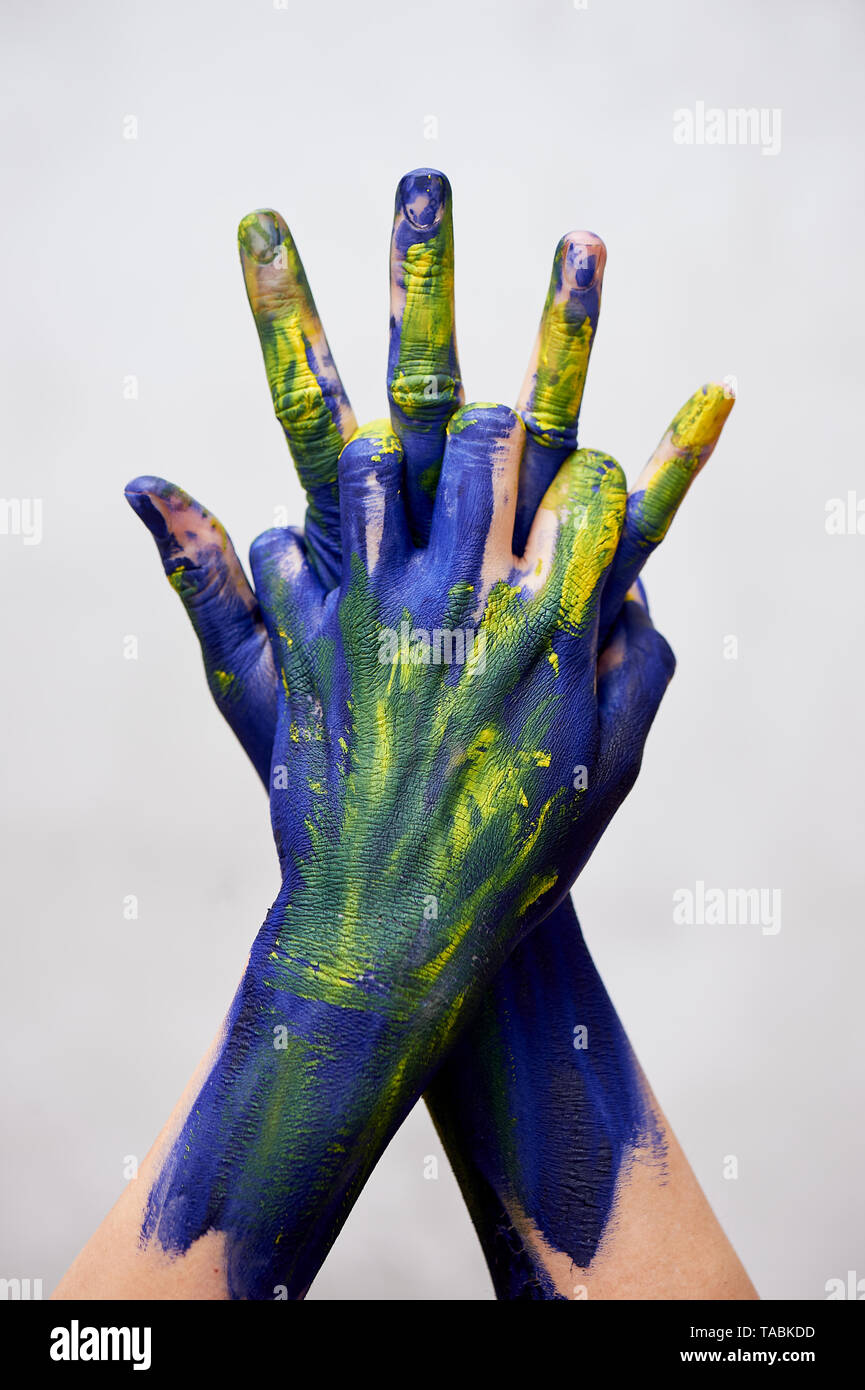 Graceful hands of the artist .Hands in blue and yellow paint. Creator ...