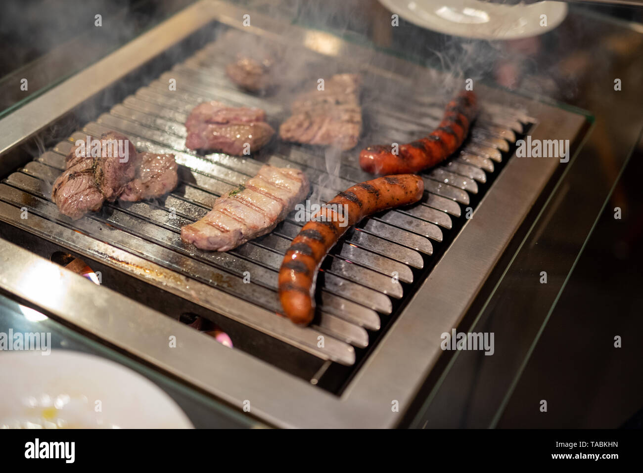 different types of meat, beef steaks and pork sausages, cooked on a grill indoor Stock Photo Alamy