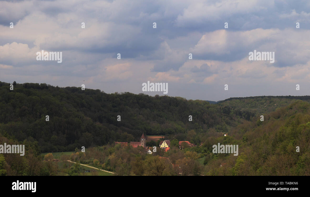 A view of buildings and houses nestled in the hills and trees seen from the garden in the town of Rothenburg ob der Tauber in Germany. Stock Photo