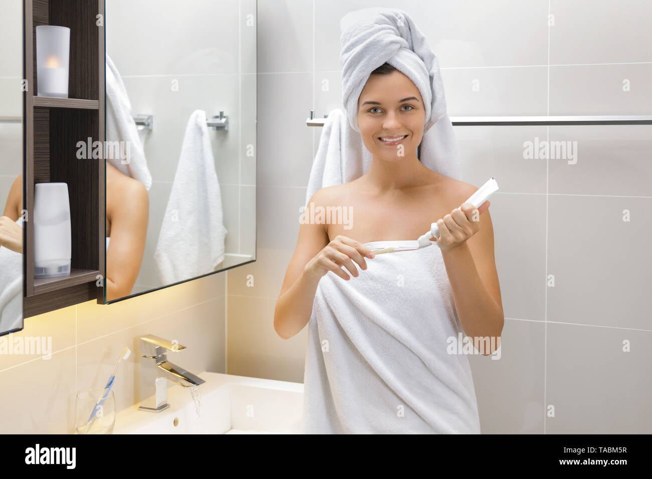 Woman  in the bathroom during her daily tooth brushing routine Stock Photo