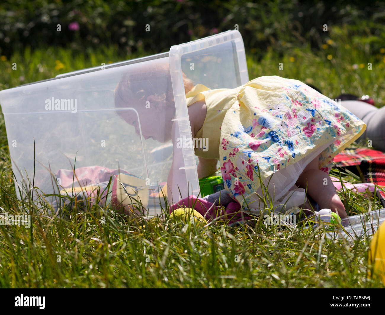 Baby girl playing in a toybox in the garden. Stock Photo