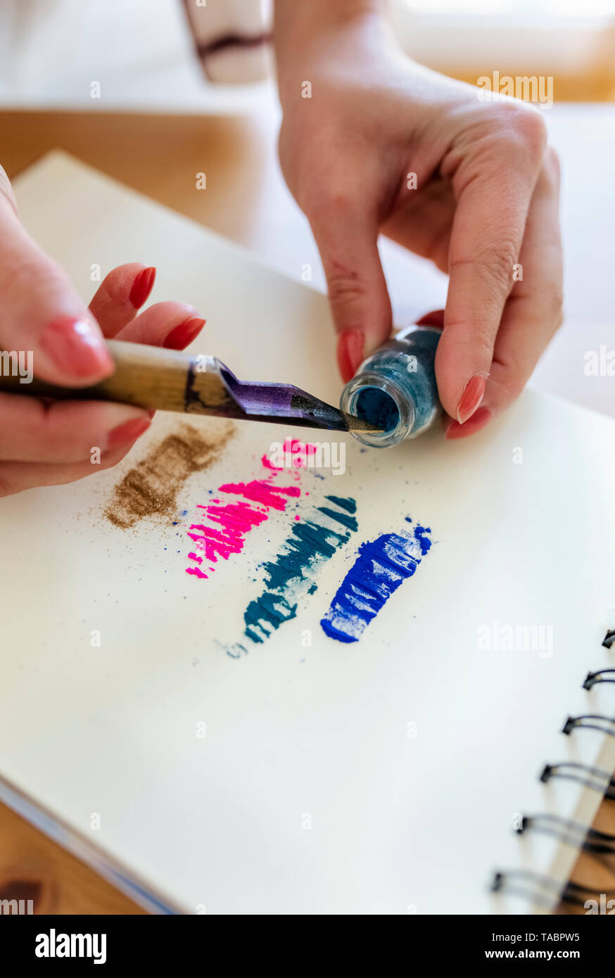 Woman's hand applying colour pigments at colouring book Stock Photo