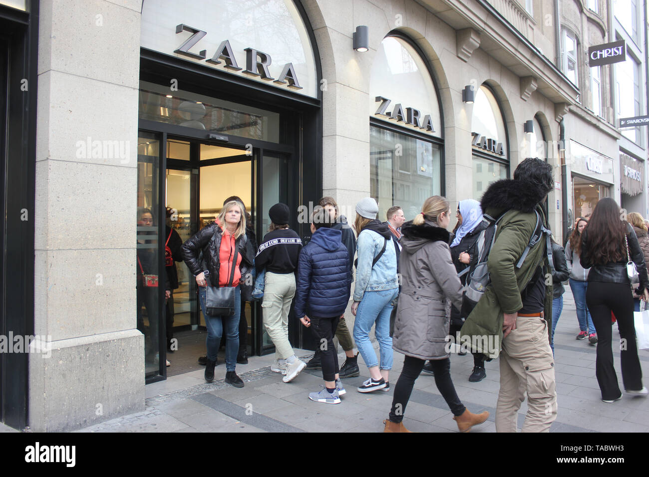 Shopping scene - mixed people, consumers, entering and passing by at Zara store in Munich shopping zone. Stock Photo