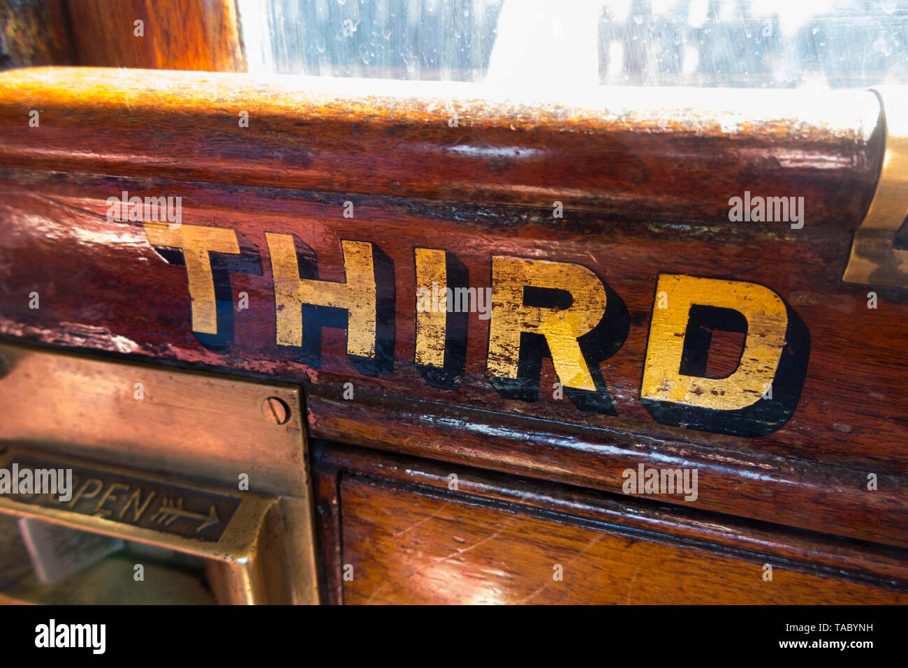 The word Third (class) painted in gold letters / lettering on the slam door with catch of an old vintage steam train carriage. England UK. (99) Stock Photo