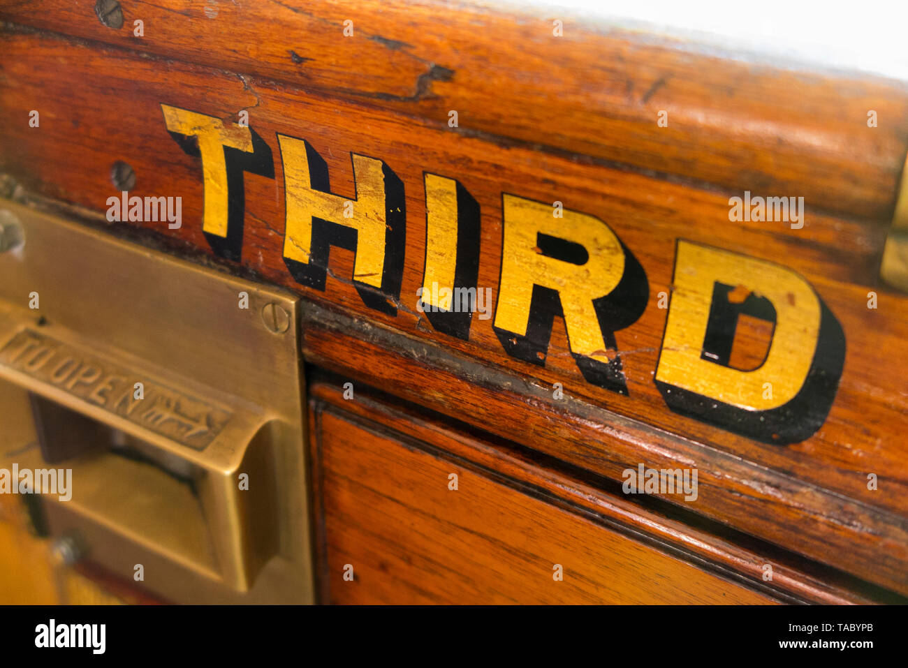The word Third (class) painted in gold letters / lettering on the slam door with catch of an old vintage steam train carriage. England UK. (99) Stock Photo