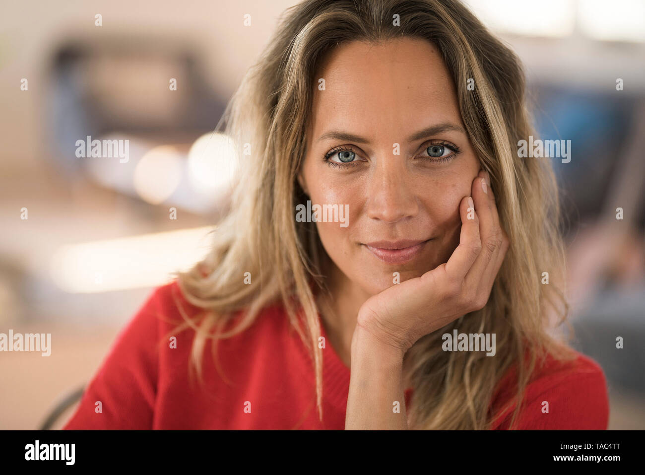 Portrait of smiling blond woman resting her head on the hand Stock Photo