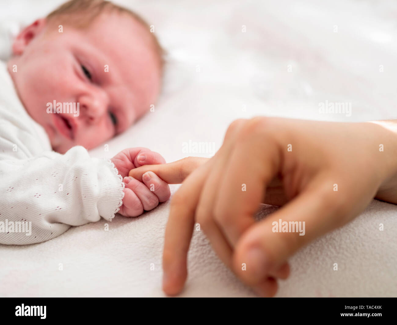 Newborn girl holding mothers finger Stock Photo