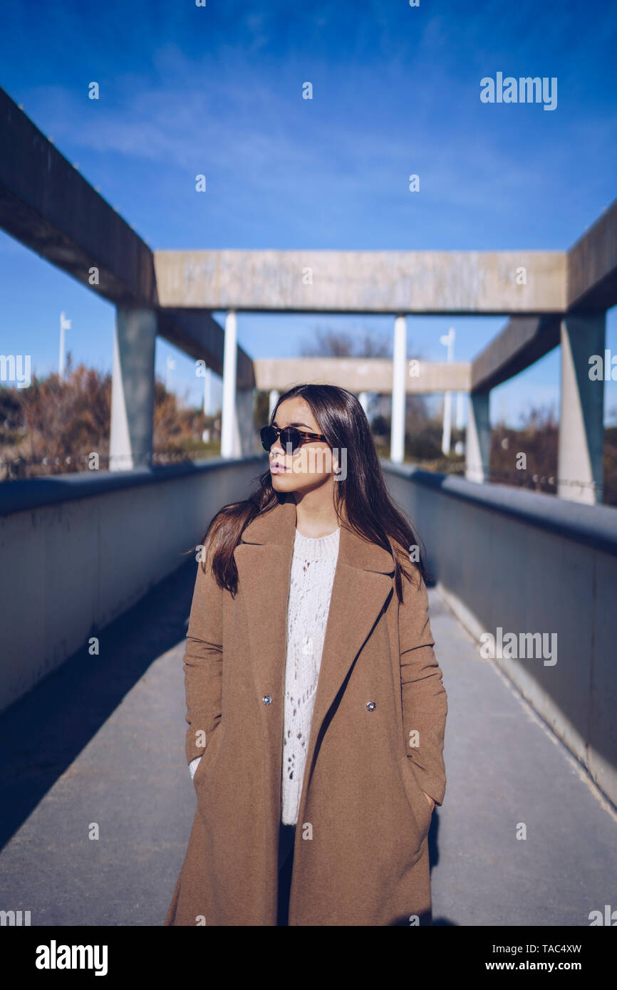 Young woman wearing coat and sunglasses standing on a bridge Stock ...
