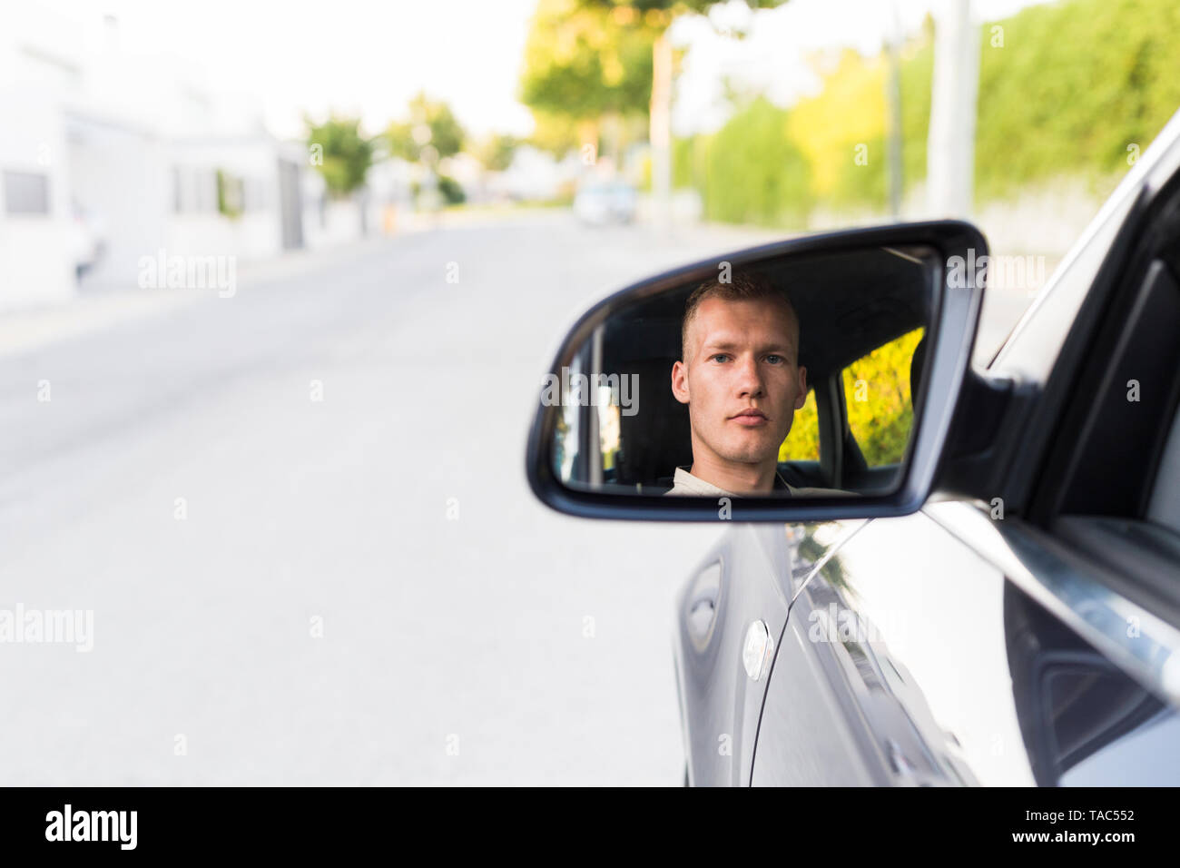 Reflection of young man in wing mirror of a car Stock Photo