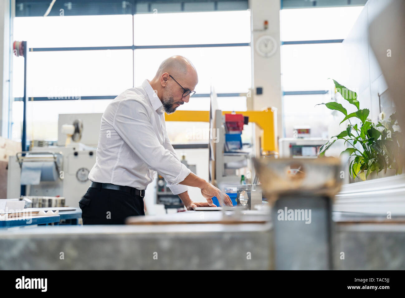 Focused businessman examining workpiece in factory Stock Photo
