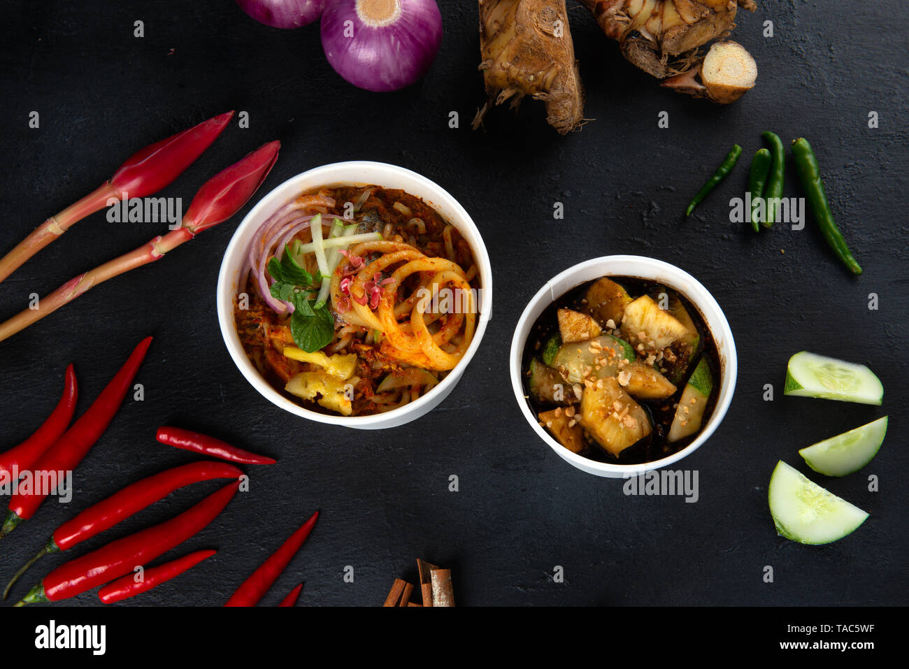 Penang Laksa Noodle Soup flat lay with ingredients on a black table. Stock Photo