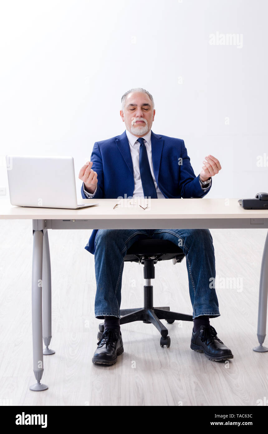 Aged businessman doing yoga exercises in the office Stock Photo - Alamy